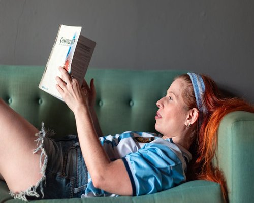 Persona relajada en el sofá de su departamento leyendo un libro con luz natural
